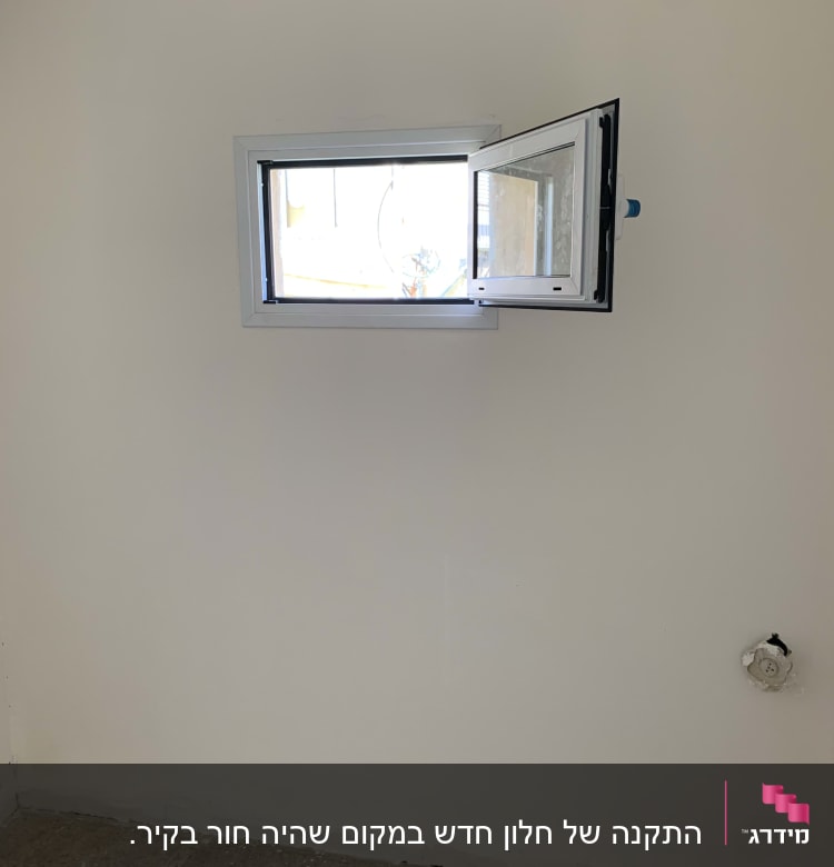 חלון אלומיניום קטן פתוח בקיר לבן